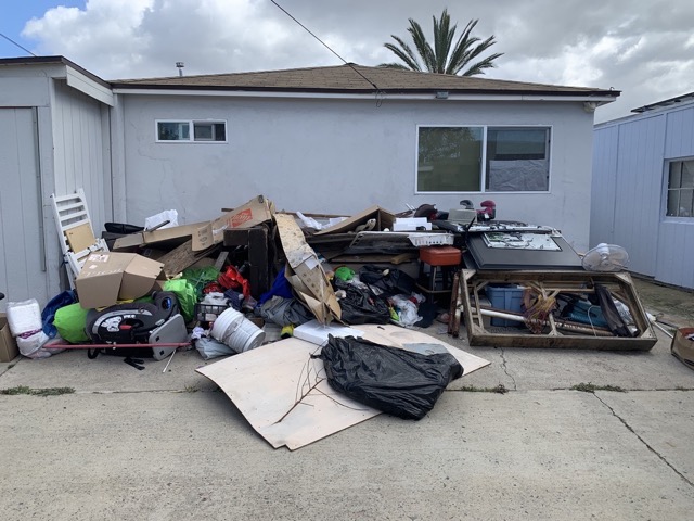 Large garage cleanout pile in front of a San Diego house