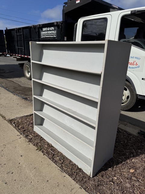 Bookcase staged beside Fred's junk removal truck