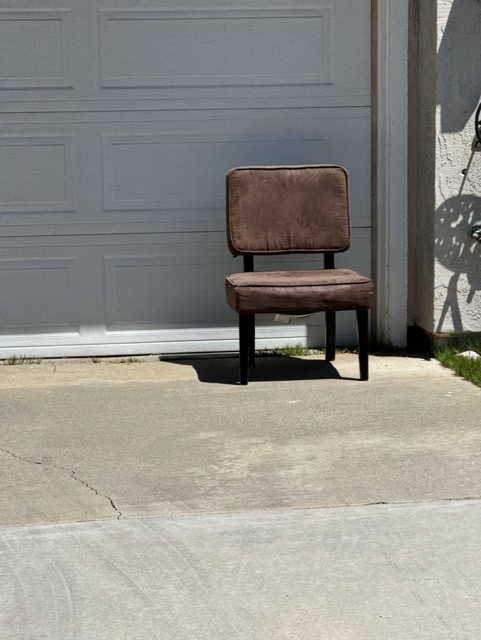 Upholstered chair in a driveway ready for hauling