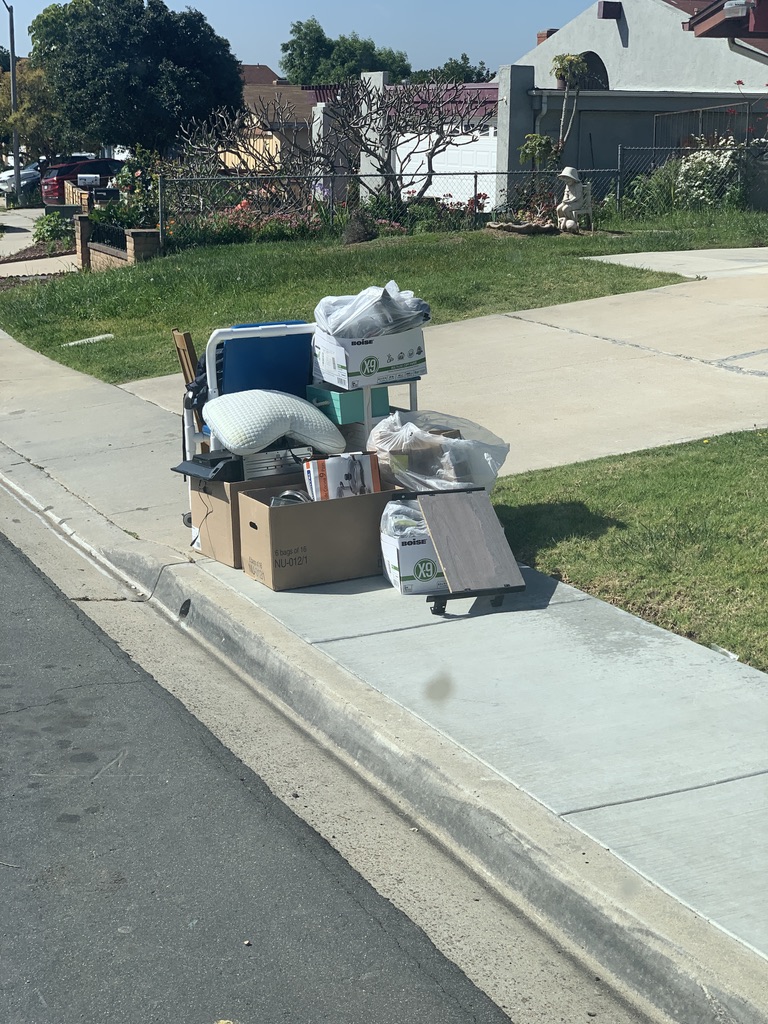 Boxes, a cooler, and household junk piled at a San Diego curb