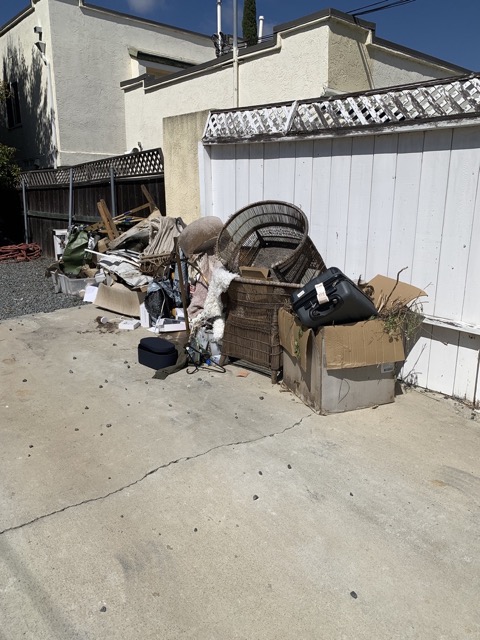 Furniture and bags piled in a driveway for hauling