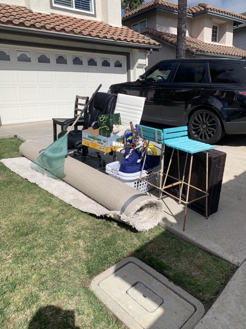 Carpet, chairs, and household junk rolled out in a driveway