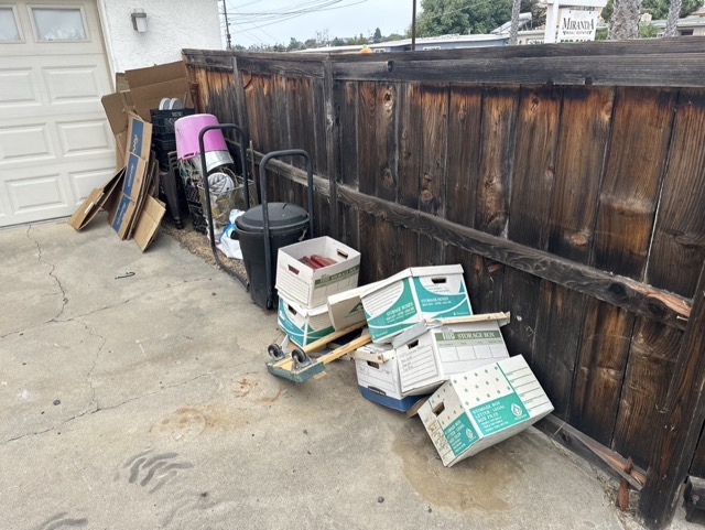 Moving boxes and bins lined up by a fence