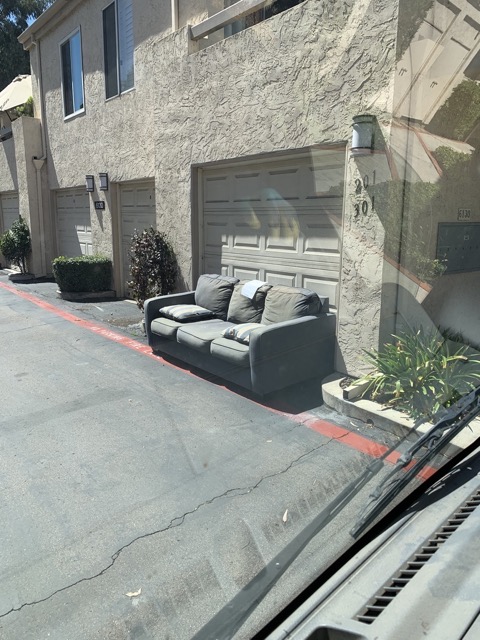 Gray loveseat staged by a garage for pickup in San Diego