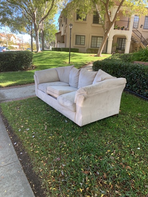 Beige sofa staged on a lawn for same day couch removal