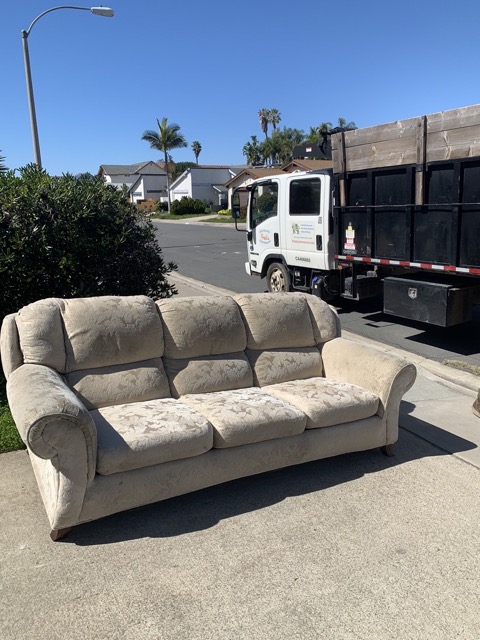 Beige sofa at the curb with Fred's junk removal truck in San Diego